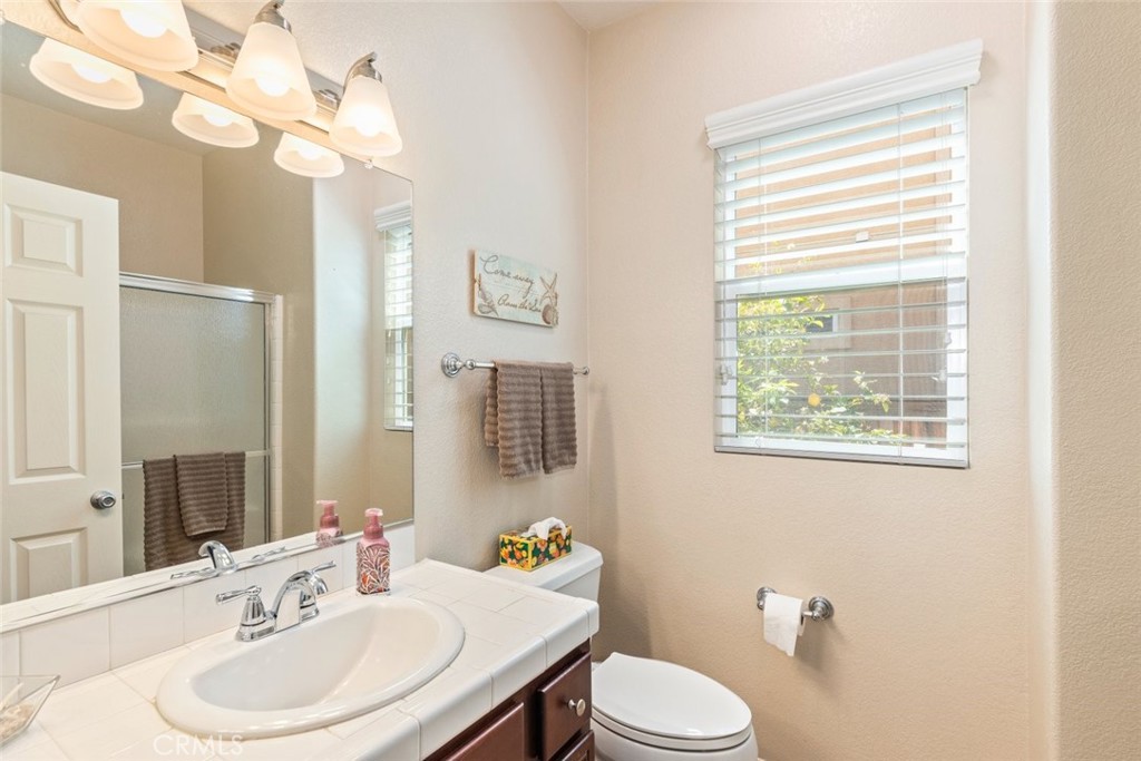 46123 Drymen Avenue Temecula, CA 92592 - Photo 19 of 42 a bathroom with a toilet a sink a mirror and a window