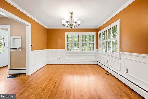 a kitchen with stainless steel appliances granite countertop a refrigerator a stove a sink a dining table and chairs with wooden floor