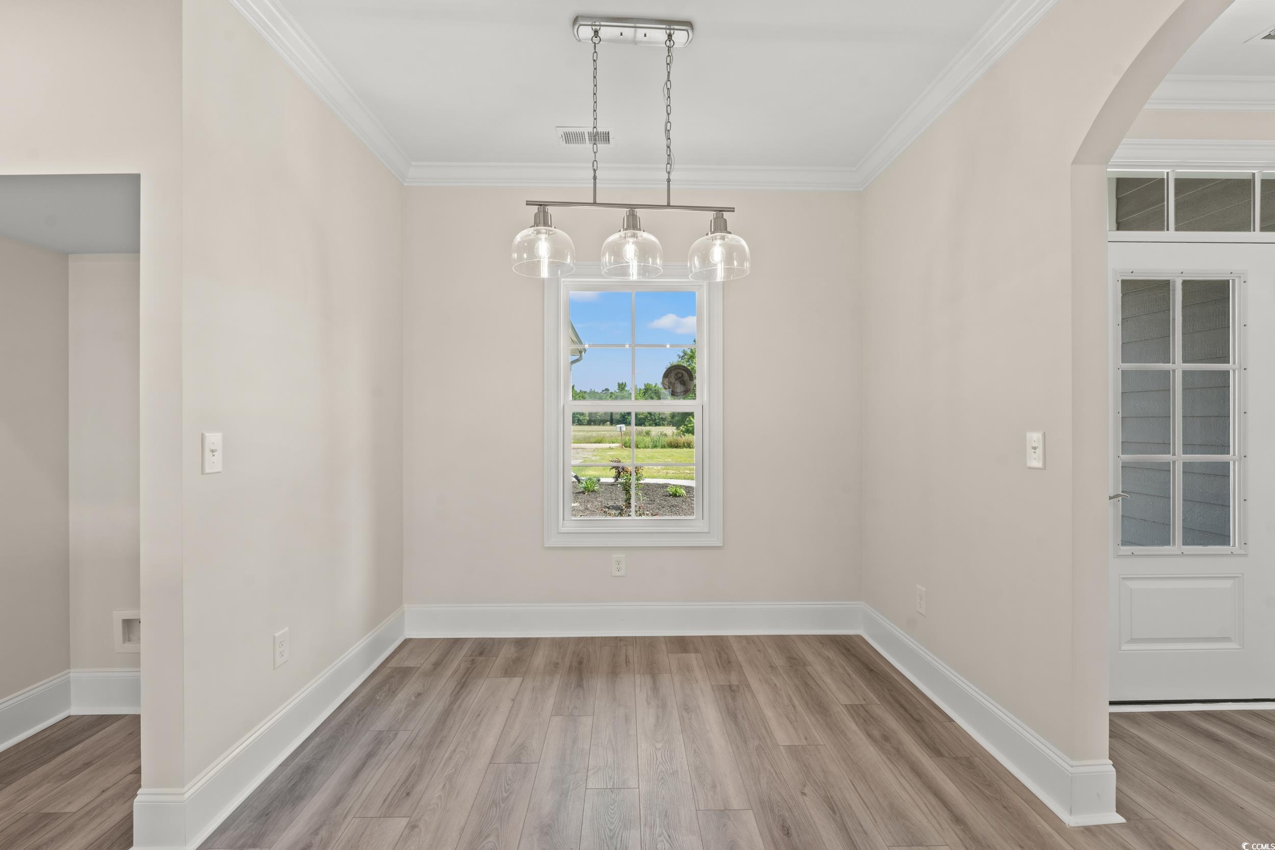 4022 Macks Road Aynor, SC 29511 - Photo 18 of 35 Unfurnished dining area with wood finished floors, ornamental molding, arched walkways, and baseboards