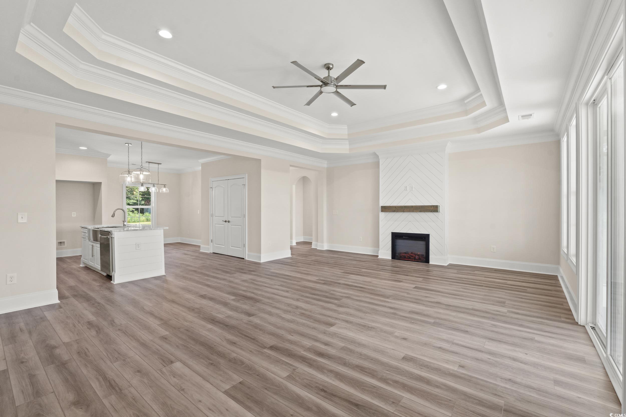4022 Macks Road Aynor, SC 29511 - Photo 2 of 35 Unfurnished living room with a tray ceiling, ceiling fan, crown molding, a fireplace, and light wood-type flooring