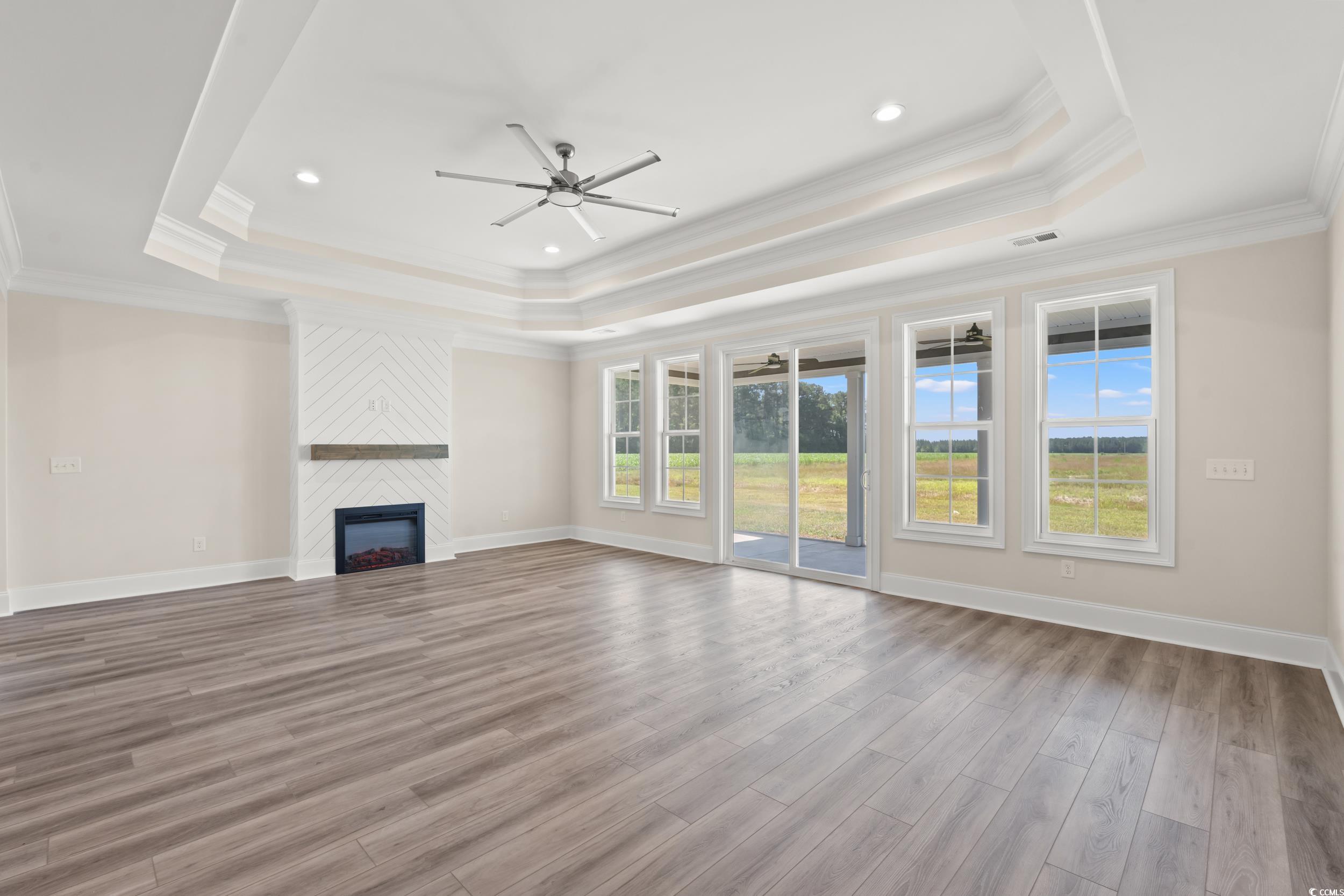 4022 Macks Road Aynor, SC 29511 - Photo 4 of 35 Unfurnished living room with a tray ceiling, ceiling fan, wood finished floors, ornamental molding, and a fireplace