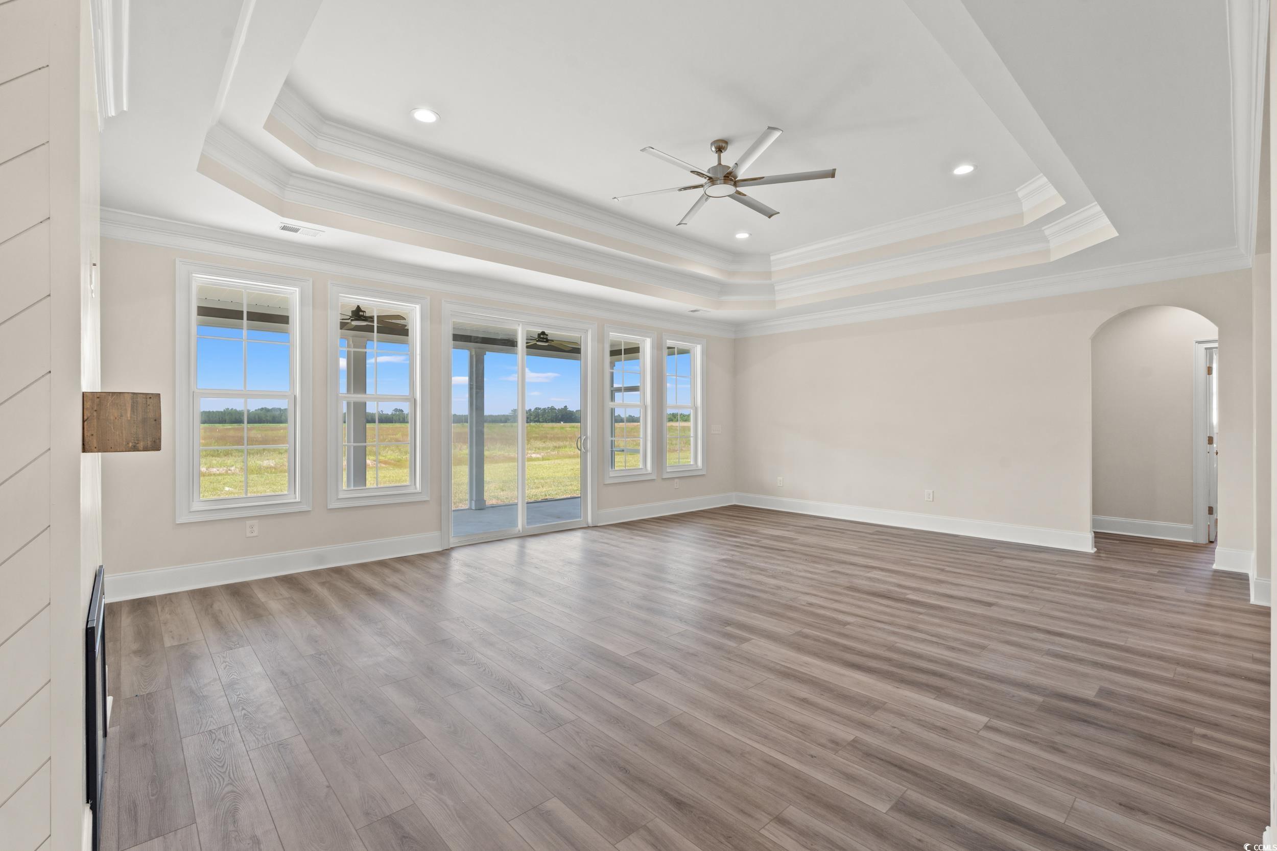 4022 Macks Road Aynor, SC 29511 - Photo 5 of 35 Empty room with a tray ceiling, ceiling fan, arched walkways, crown molding, and wood finished floors