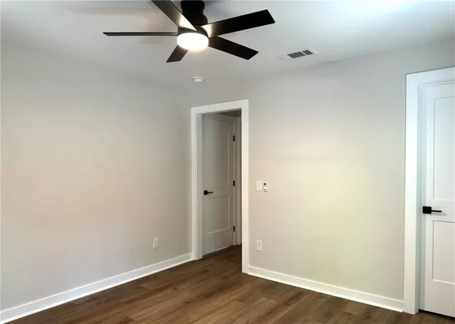 an empty room with wooden floor and a ceiling fan