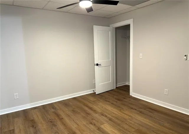 an empty room with wooden floor chandelier fan and windows