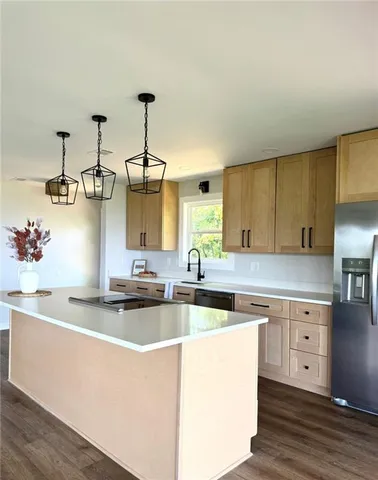 a kitchen with kitchen island granite countertop a sink cabinets and wooden floor