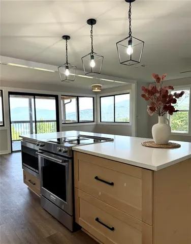 a kitchen with stainless steel appliances a stove and a large window with wooden floor