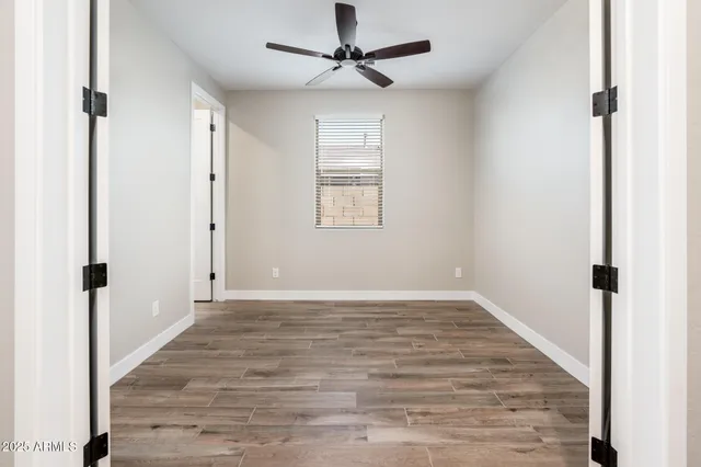a view of an empty room with window and a ceiling fan
