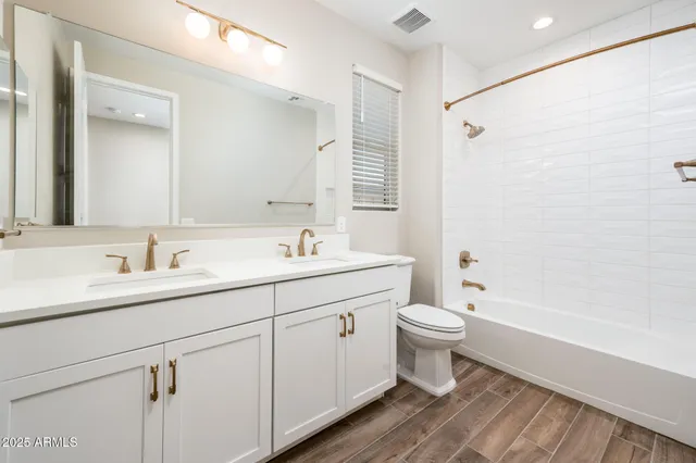 a bathroom with a double vanity sink toilet mirror and shower