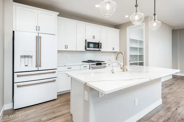 a kitchen with stainless steel appliances granite countertop a sink a stove a refrigerator and island with wooden floor