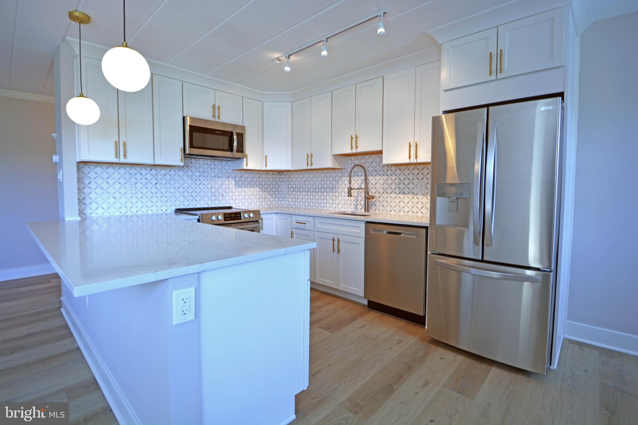 a kitchen with stainless steel appliances granite countertop a refrigerator a stove a sink and a microwave