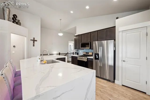 a large kitchen with a refrigerator a stove top oven a sink dishwasher and wooden cabinets with wooden floor