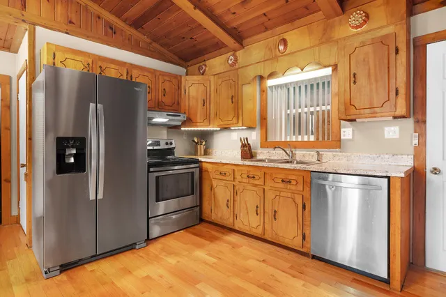 a view of an empty room with wooden floor ceiling fan