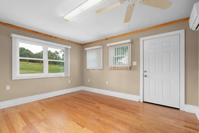 a view of an empty room with window and chandelier fan