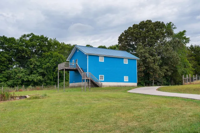 an aerial view of a houses with outdoor space and trees all around