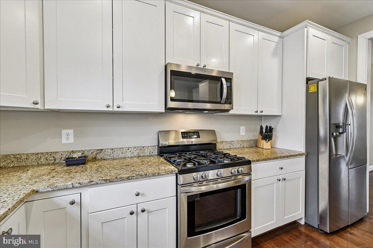 7526 Gilley Terrace Rosedale, MD 21237 - Photo 13 of 43 a kitchen with granite countertop white cabinets stainless steel appliances and wooden floor