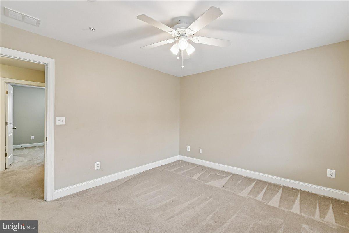 7526 Gilley Terrace Rosedale, MD 21237 - Photo 29 of 43 an empty room with a chandelier fan and windows