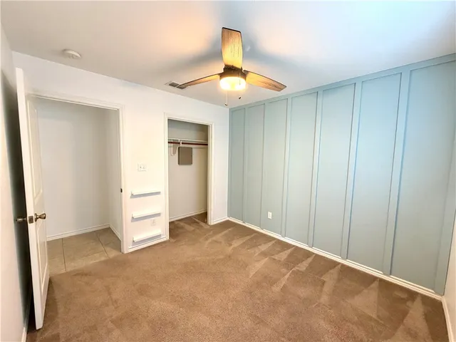 an empty room with closet and a chandelier fan