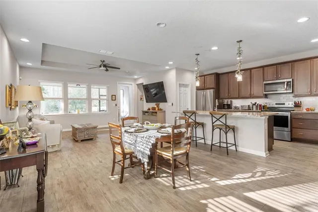 a kitchen with stainless steel appliances kitchen island granite countertop a dining table chairs refrigerator and sink