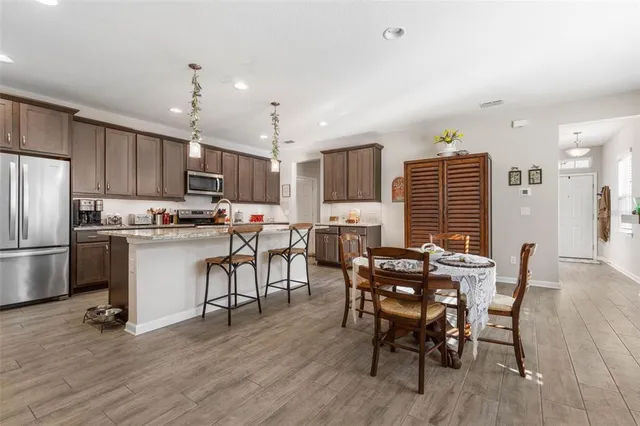 a kitchen with stainless steel appliances a table chairs refrigerator and chairs