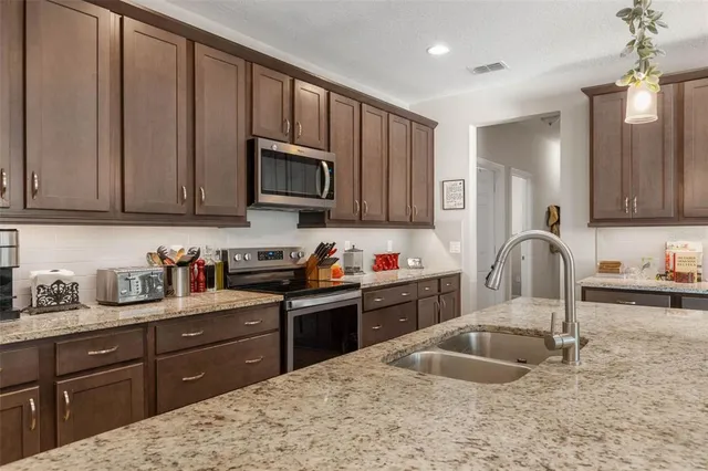 a kitchen with granite countertop a sink stainless steel appliances and cabinets