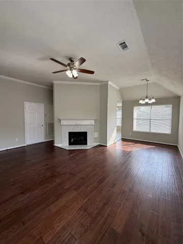 an empty room with wooden floor fireplace and windows