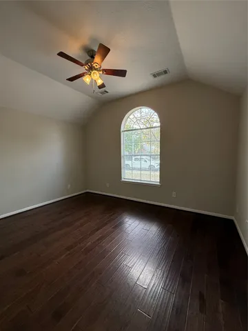 an empty room with wooden floor chandelier fan and windows