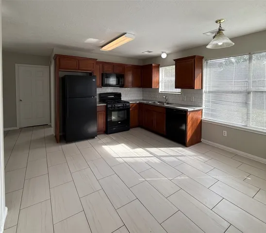 a large kitchen with stainless steel appliances granite countertop a refrigerator and a stove top oven