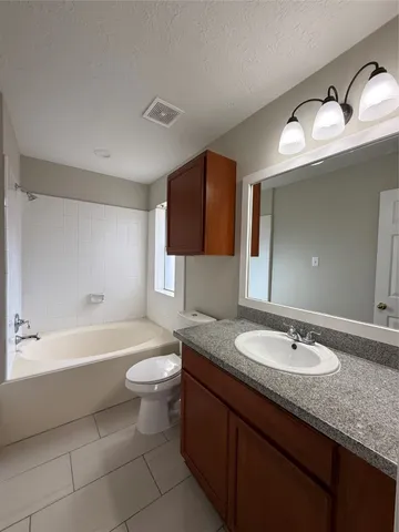 a bathroom with a granite countertop sink mirror vanity bathtub and a toilet