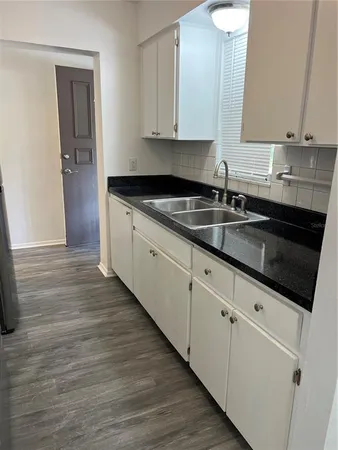 a kitchen with granite countertop white cabinets and sink