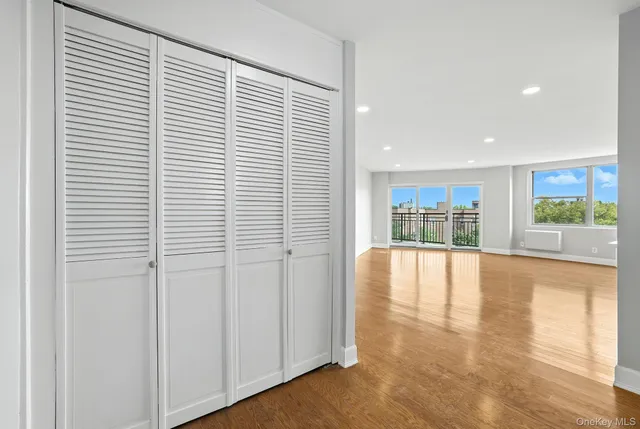 a view of an empty room with a window and wooden floor