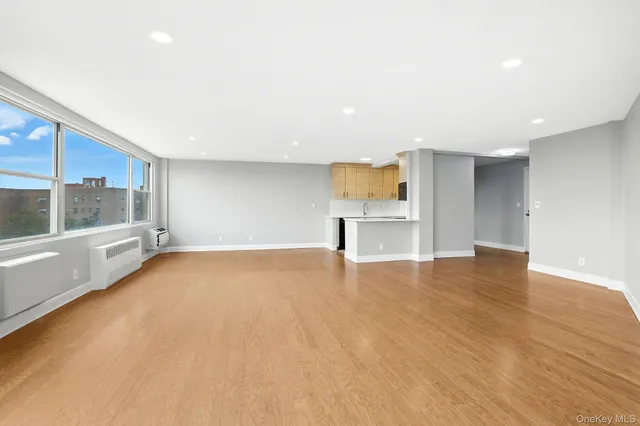a view of an empty room with a window and wooden floor