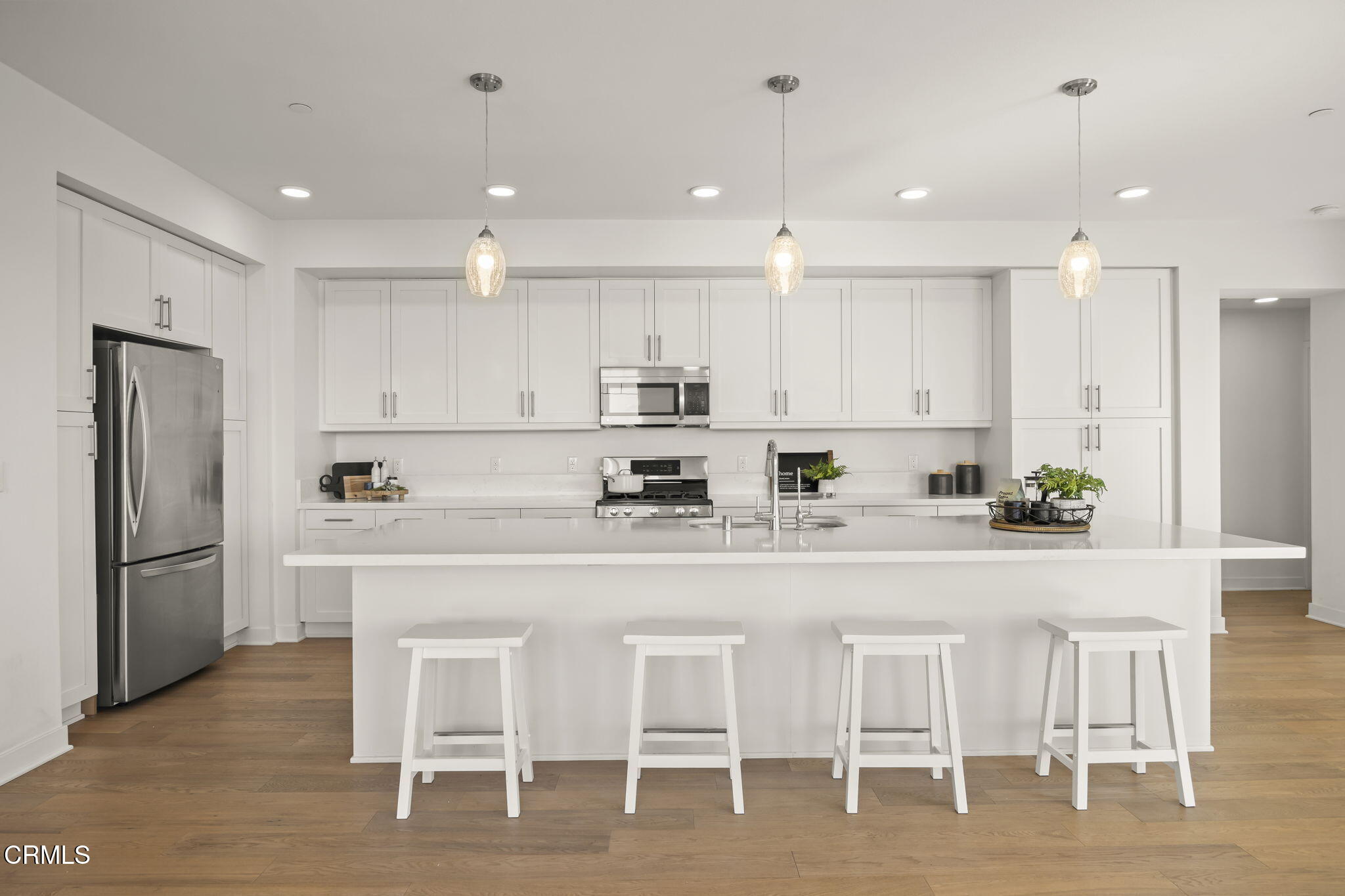 2800 Wagon Wheel Road, Unit 404 Oxnard, CA 93036 - Photo 11 of 43 a white kitchen with a dining table chairs wooden cabinets and stainless steel appliances