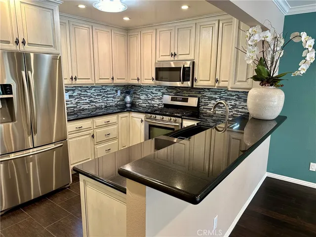 a kitchen with stainless steel appliances granite countertop a refrigerator a stove and a sink