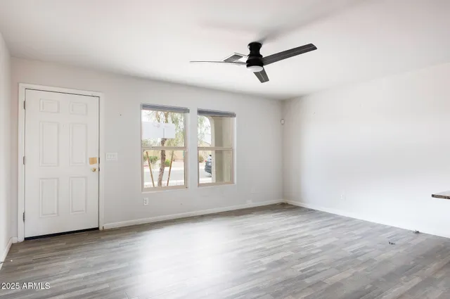 a view of empty room with wooden floor and fan