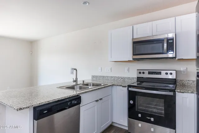 a kitchen with granite countertop a stove sink and microwave