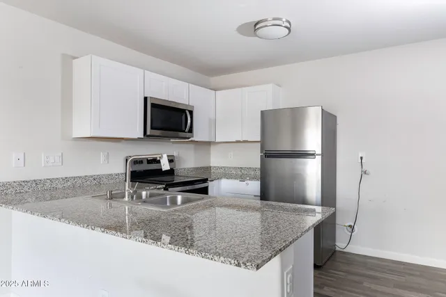 a kitchen with stainless steel appliances granite countertop a sink a refrigerator and a granite counter tops