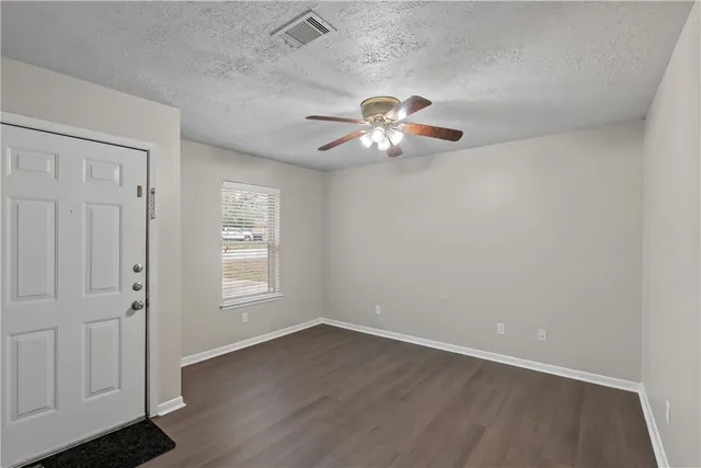 an empty room with wooden floor chandelier fan and windows