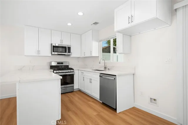 a kitchen with cabinets stainless steel appliances and wooden floor