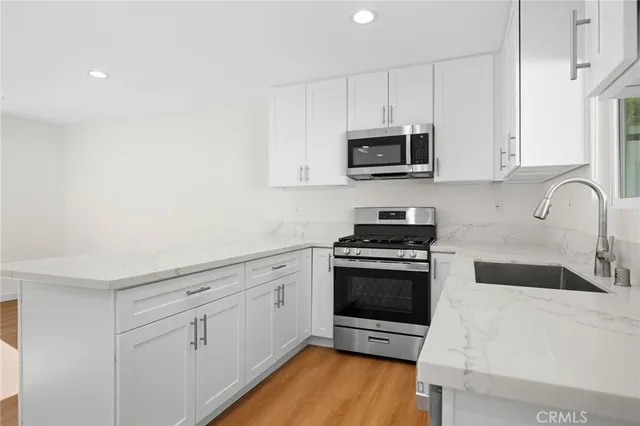 a kitchen with stainless steel appliances granite countertop a stove a sink and a microwave