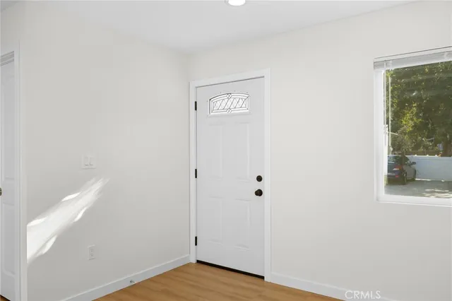 a view of an empty room with wooden floor and a window