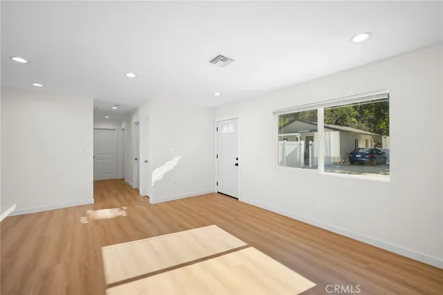 a view of a big room with wooden floor and windows
