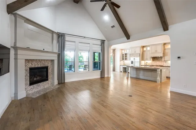 a view of an empty room and kitchen with a fireplace