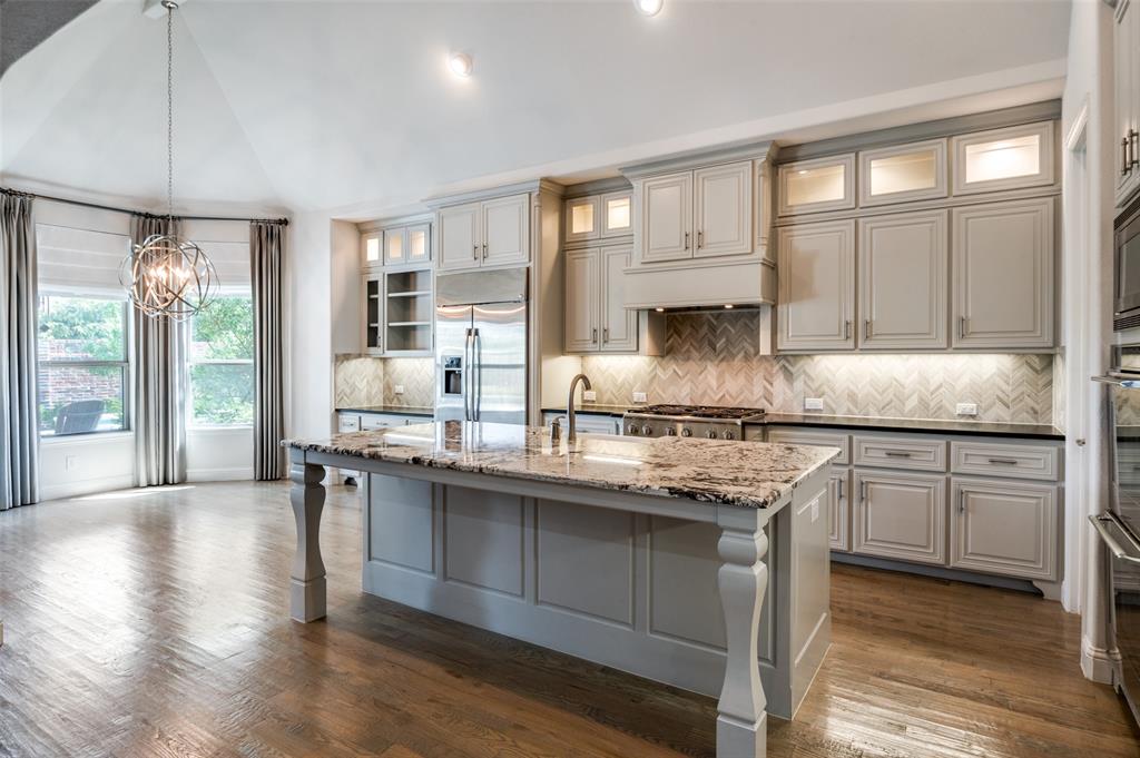 10482 Tobias Lane Frisco, TX 75033 - Photo 4 of 40 a kitchen with stainless steel appliances granite countertop a stove a sink and white cabinets with wooden floor