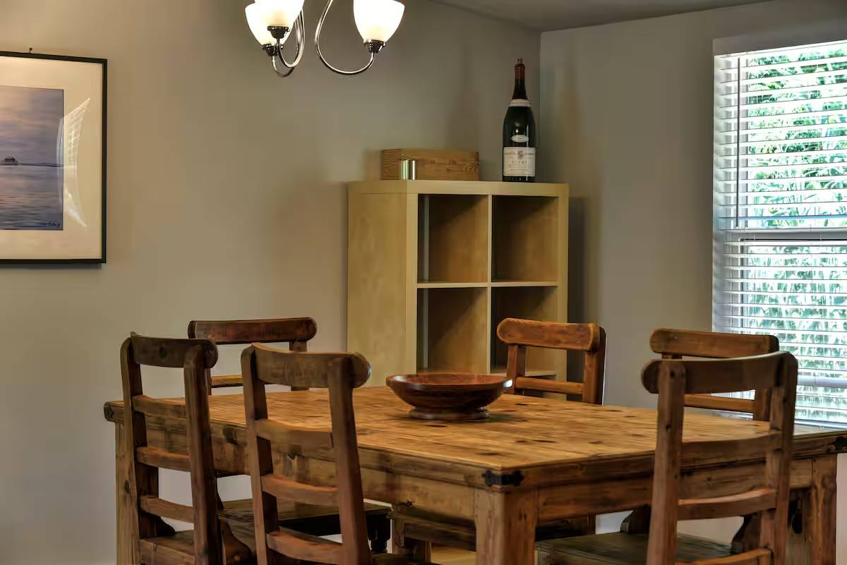 8807 High Valley Road Austin, TX 78737 - Photo 10 of 22 A spacious dining area with rustic wood furnishings, illuminated by a classic chandelier.