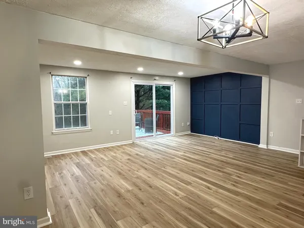 a view of an empty room with a window and chandelier fan