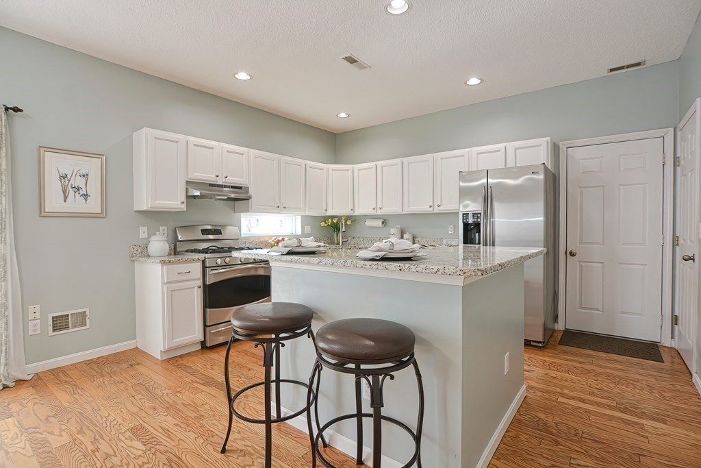 14 Robbins Road Foxboro, MA 02035 - Photo 3 of 42 a kitchen with kitchen island a stove a refrigerator and white cabinets with wooden floor