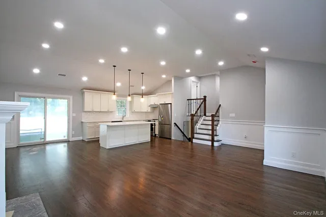 an open dining hall with wooden floor and a kitchen view