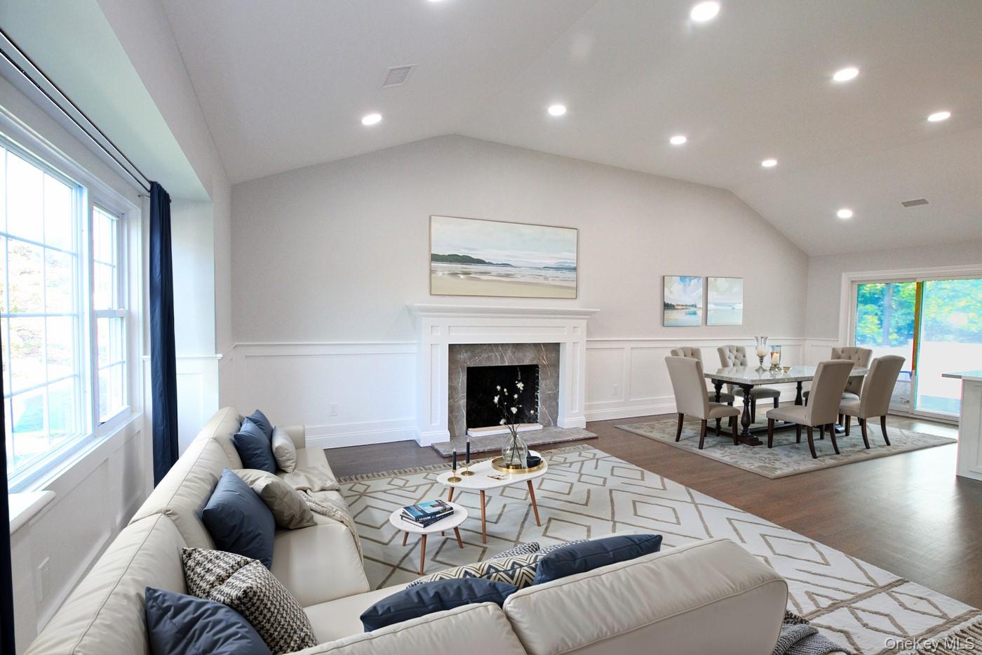 16 Eleanor Road Plainview, NY 11803 - Photo 7 of 27 Living area featuring wainscoting, wood finished floors, lofted ceiling, a premium fireplace, and sliders to back yard (virtually staged)