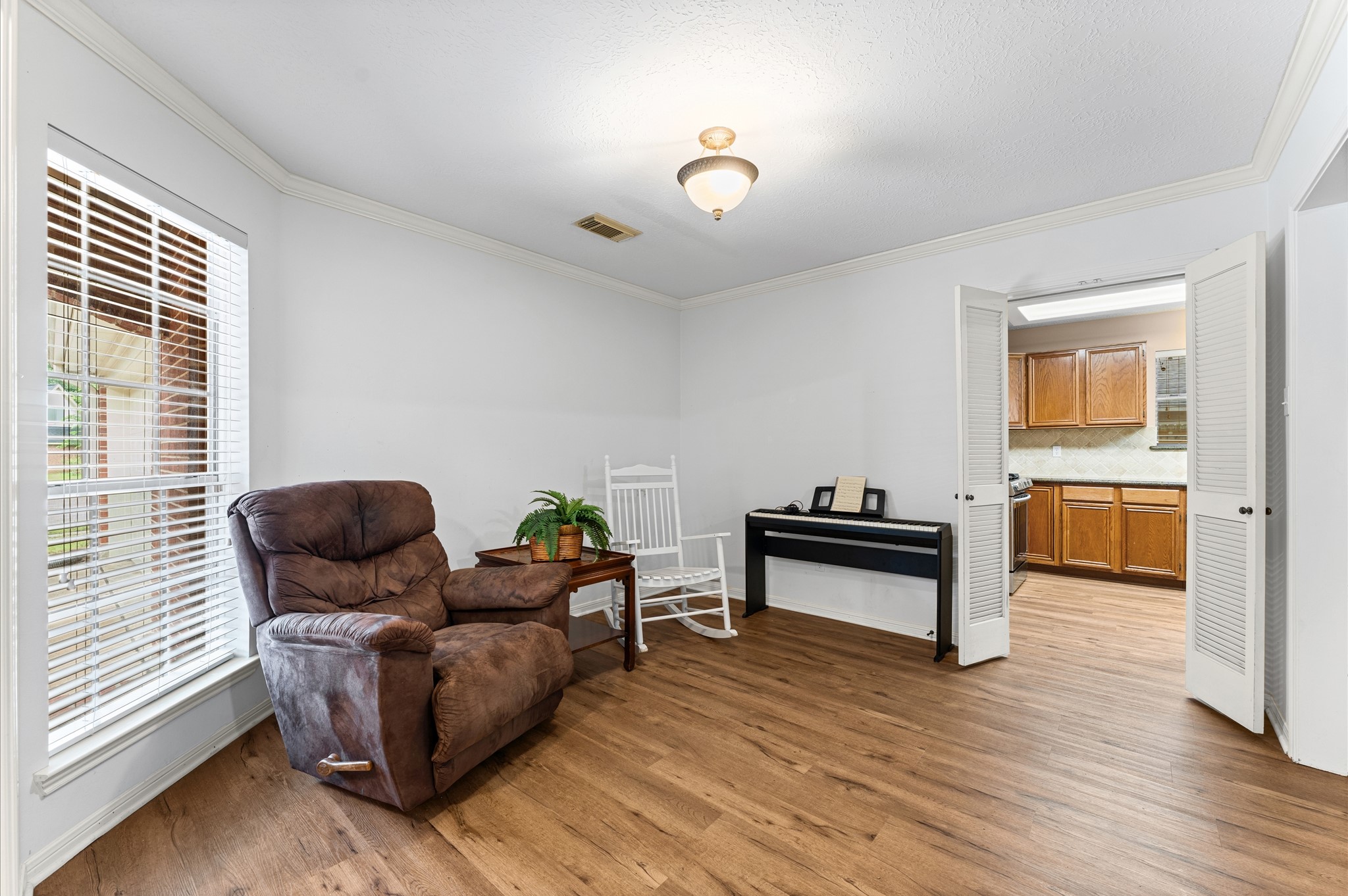 17618 Mill Springs Drive Spring, TX 77379 - Photo 10 of 26 This cozy room features hardwood floors, a large window with blinds for natural light, and a comfortable seating area with a recliner and rocking chair. Double doors open to an adjacent kitchen, enhancing the open layout.