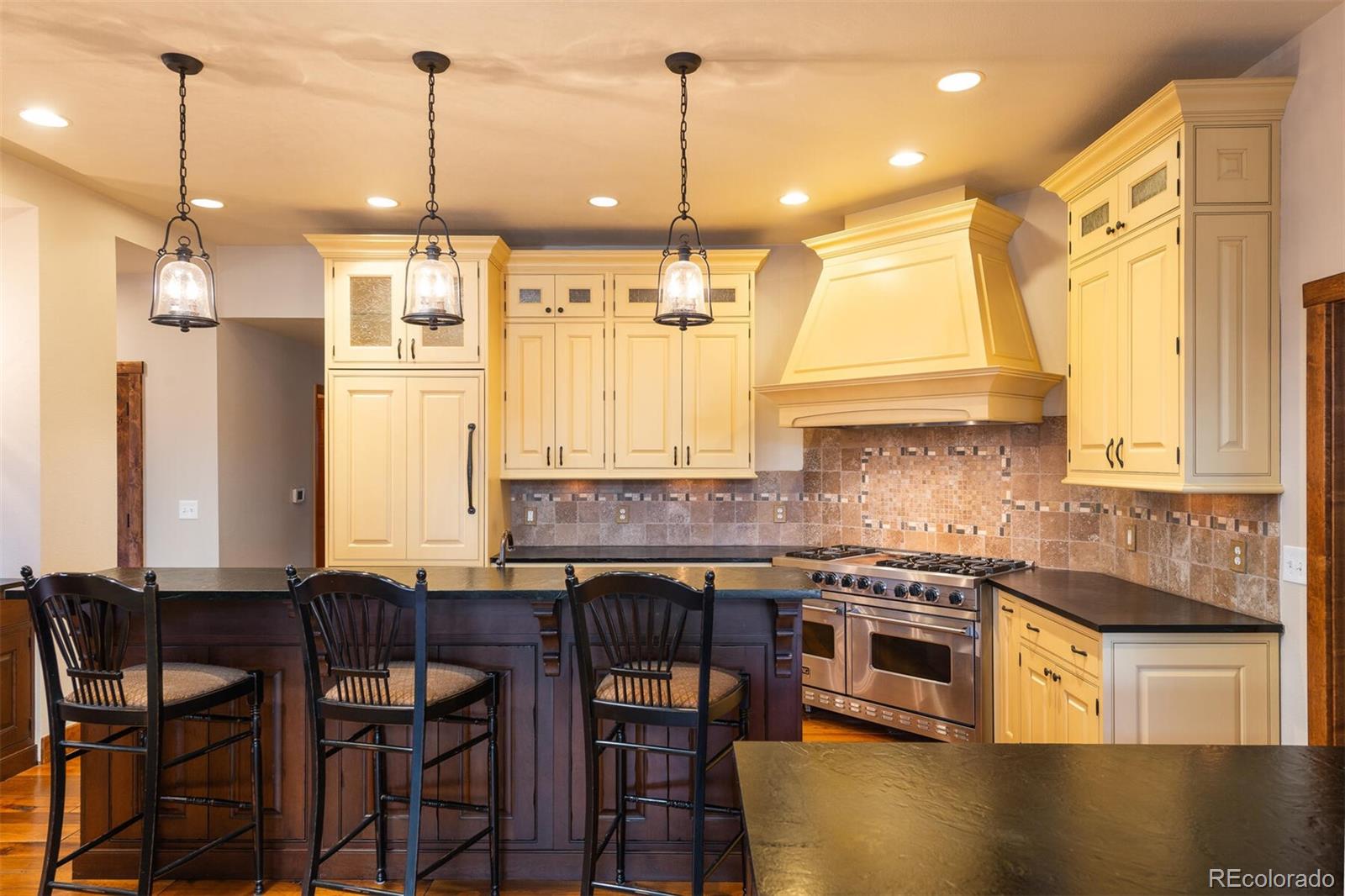 9905 Isabelle Road Lafayette, CO 80026 - Photo 21 of 38 a kitchen with stainless steel appliances granite countertop a stove a sink a refrigerator a dining table and chairs